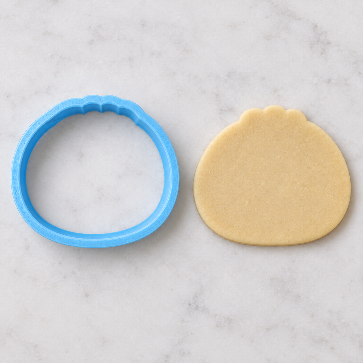 Blue dumpling cutter beside the plain raw cookie dough shape it cuts