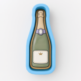 A blue mold or cookie cutter shaped like a champagne bottle with a label.