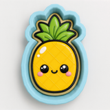 A cookie cutter in the shape of a pineapple with a smiling face and a leafy top.