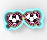 A pair of heart-shaped sunglasses with a soccer ball pattern on the lenses.