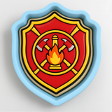 A shield-shaped cookie cutter with a red and yellow design featuring a fire extinguisher and flames.