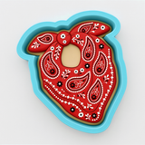 A red paisley-patterned cookie cutter in a blue mold.