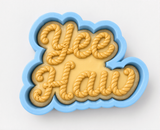 A cookie cutter shaped like the word "Yeehaw" made of frosting.