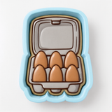A blue container with six brown egg-shaped cookies arranged inside it.