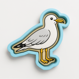A cartoon seagull is depicted in a blue and yellow cutout shape against a white background.