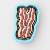 A blue cookie cutter shaped like a piece of bacon, with a stylized design featuring red and white stripes.