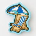 A blue and white striped beach chair and umbrella are depicted in the image.