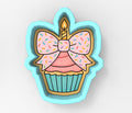 A cookie cutter in the shape of a cupcake with a candle and sprinkles on top.