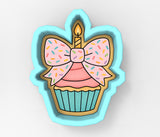 A cookie cutter in the shape of a cupcake with a candle and sprinkles on top.