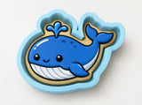 A blue and white cartoon-style cookie cutter shaped like a whale.