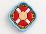 A colorful life preserver-shaped object with a blue rim and a red and yellow center, placed on a white background.