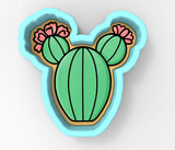 a cookie shaped like a cactus with pink flowers