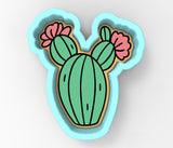 a green cactus with a pink flower on it
