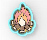 A blue cookie cutter shaped like a campfire with a fire burning on it.
