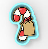 A cookie cutter in the shape of a candy cane with a brown tag attached to it.