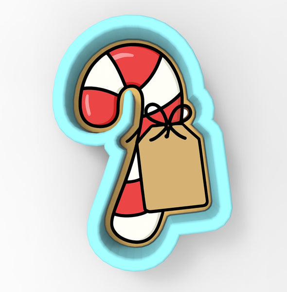 A cookie cutter in the shape of a candy cane with a brown tag attached to it.