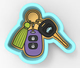 A cookie cutter-shaped keychain with a car key and a tassel key attached to it.