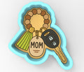 A cookie cutter shaped like a car key with a tassel and a keyring attached to it, along with a key-shaped tag that says "MOM".