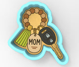 A cookie cutter shaped like a car key with a tassel and a keyring attached to it, along with a key-shaped tag that says "MOM".
