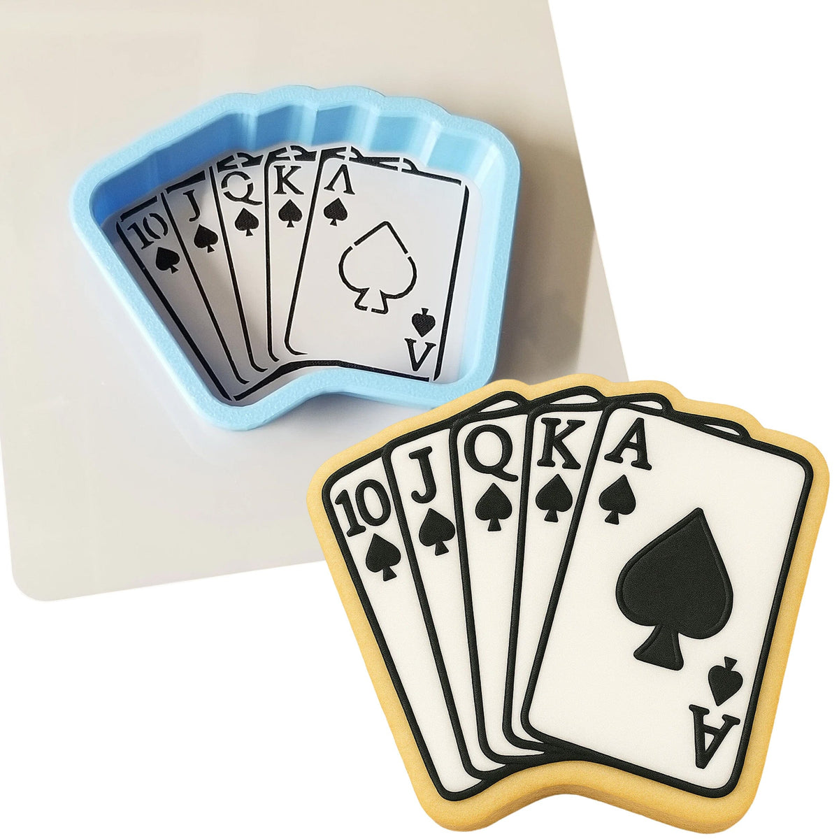 a cookie shaped like a playing card next to a cookie cutter