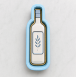 A blue cookie cutter shaped like a wine bottle with a leaf design on it.