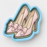 A pair of pink high-heeled shoes with bows on the toe.