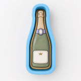 A blue mold or cookie cutter shaped like a champagne bottle with a label.