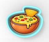 A bowl of cheese dip with a slice of tortilla chip placed in it.