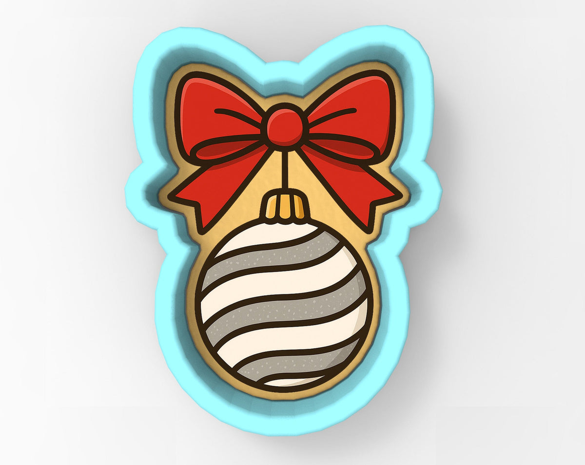 A cookie cutter in the shape of a cat's head with a red bow and a striped ornament.