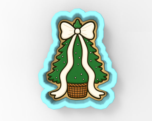 A cookie cutter-shaped Christmas tree with a bow, placed in a basket.