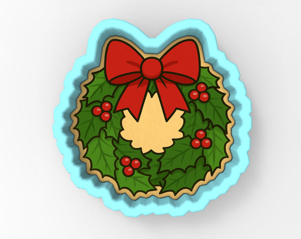 A wreath-shaped cookie cutter with a red bow and holly leaves, berries, and a yellow center, set against a light blue background.