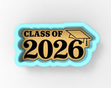 A cookie cutter shaped like the text "CLASS OF 2026" with a graduation cap on top, representing a graduation or commencement event.