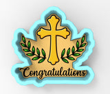 a cookie cutter shaped like a cross with a laurel wreath and the word "Congratulations" written on it.