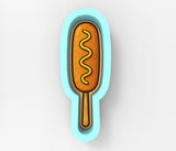 a hot dog on a stick with mustard on it