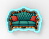 A blue velvet couch with red throw pillows, set against a light blue background.