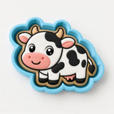 A cookie cutter in the shape of a cartoon cow with a pink nose and spots.