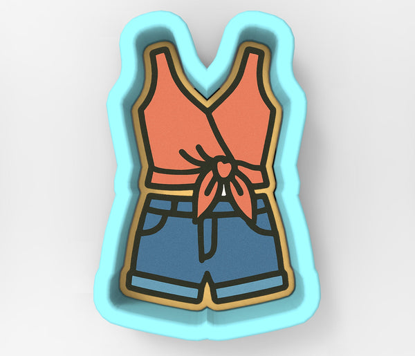 A cookie cutter in the shape of a woman's torso, with a red top and blue shorts.