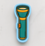 A blue and green flashlight-shaped cookie cutter is shown against a white background.