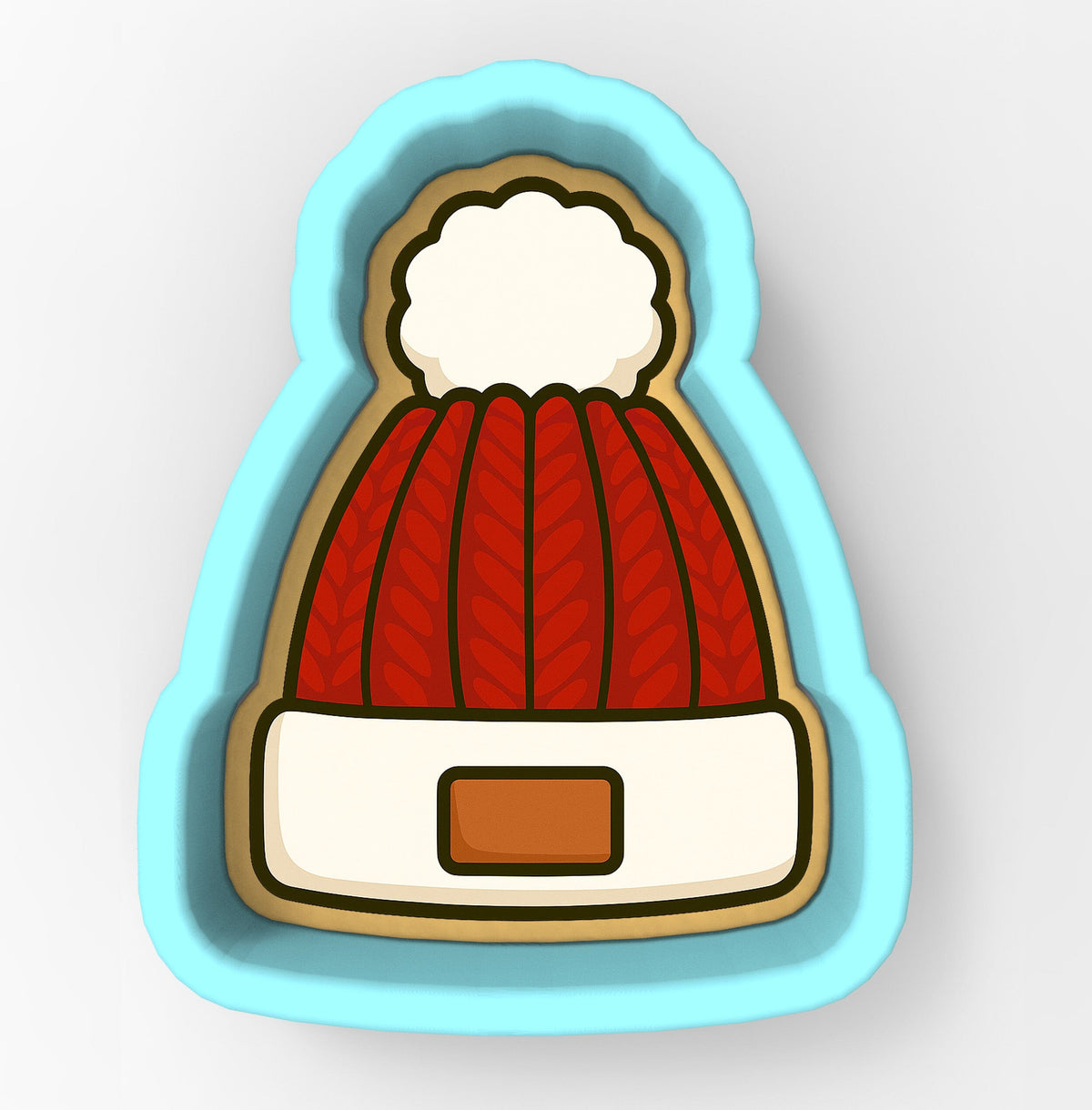 A cookie cutter in the shape of a red knit hat with a white pom pom.