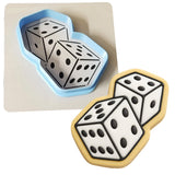 a cookie with a cookie cutter next to a cookie with two dices on it
