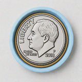 A silver-colored coin with a profile portrait of a man, surrounded by a blue border.
