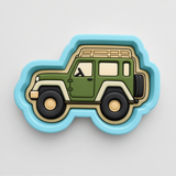 A green and beige toy car-shaped cookie cutter with a blue border.