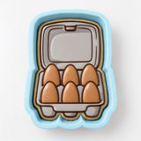 A blue container with six brown egg-shaped cookies arranged inside it.