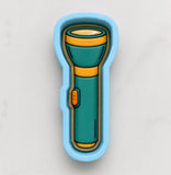 A blue and green flashlight-shaped cookie cutter is shown against a white background.