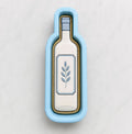 A blue cookie cutter shaped like a wine bottle with a leaf design on it.