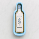 A blue cookie cutter shaped like a wine bottle with a leaf design on it.