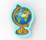 A globe-shaped cookie cutter with a gold base and a blue border, depicting a stylized representation of the Earth.