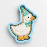 A cookie cutter shaped like a duck wearing a party hat and bow tie.