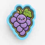 A blue and green cookie cutter shaped like a bunch of purple grapes with a smiling face.