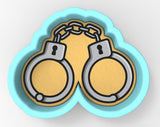 A cookie cutter in the shape of a pair of handcuffs, with a yellow background and a blue outline.